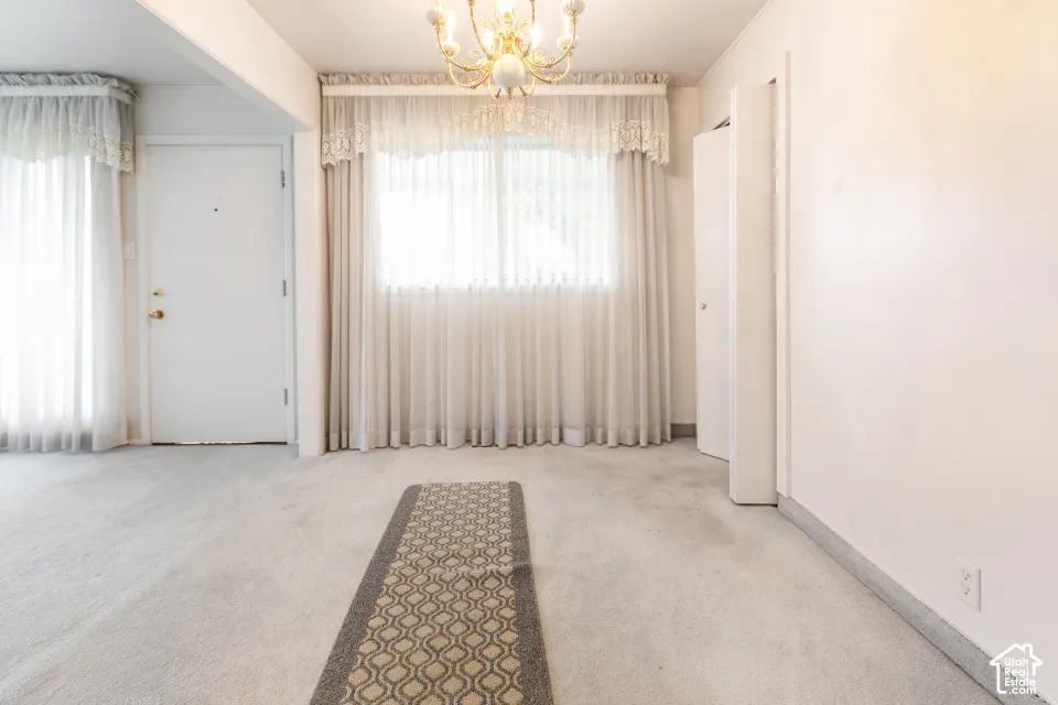 Interior room featuring neutral wall-to-wall carpeting, an integrated bi-fold door closet, and a multi-arm chandelier with decorative glass shades