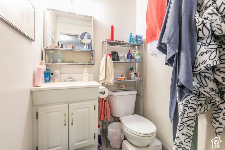 Bathroom featuring a white vanity cabinet with an integrated sink, a rectangular wall-mounted mirror, and a standard toilet