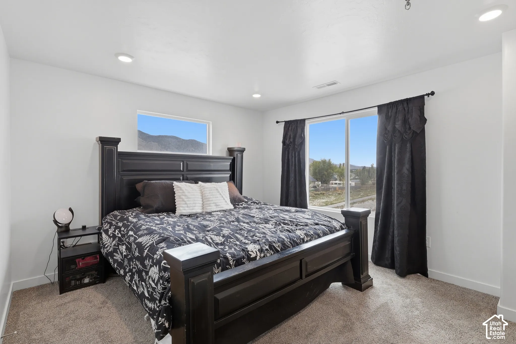 Neutral-toned carpeting, recessed ceiling lighting, and windows featuring mountain scenery