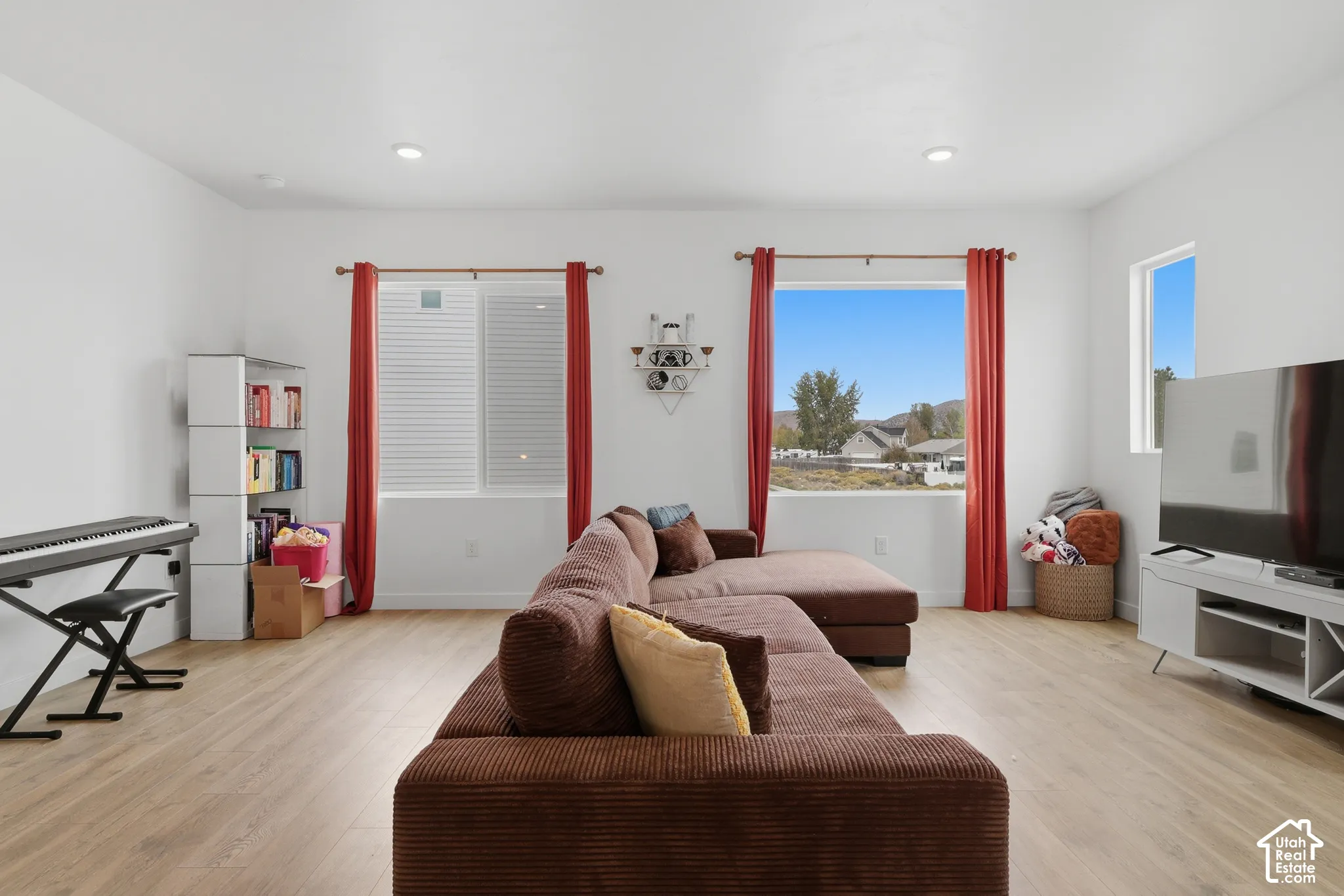Open-concept interior featuring light-tone wood-finish flooring, recessed lighting, and large windows providing natural light