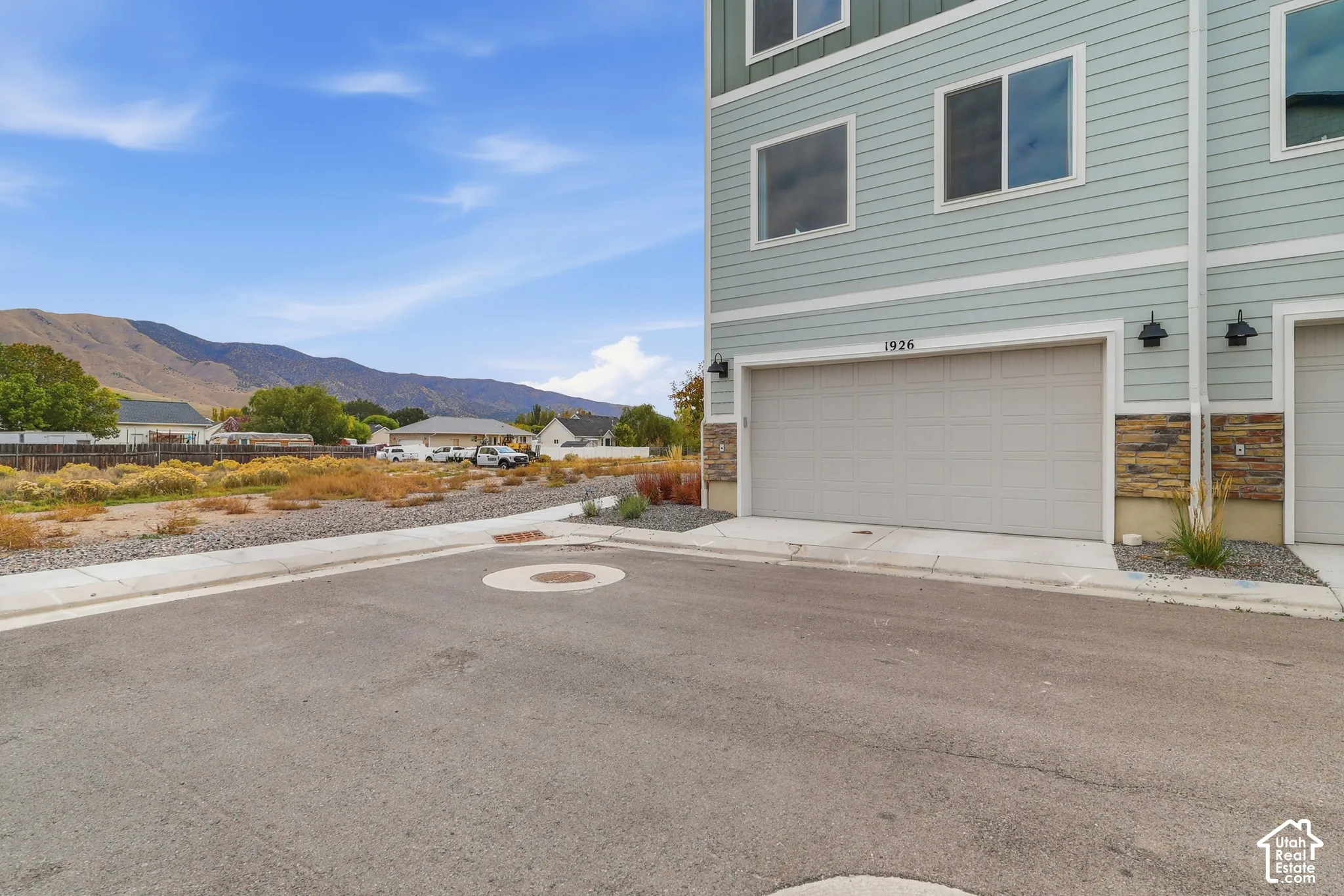 Multi-story exterior with horizontal siding, stone veneer accents, integrated two-car garage, and mountain backdrop