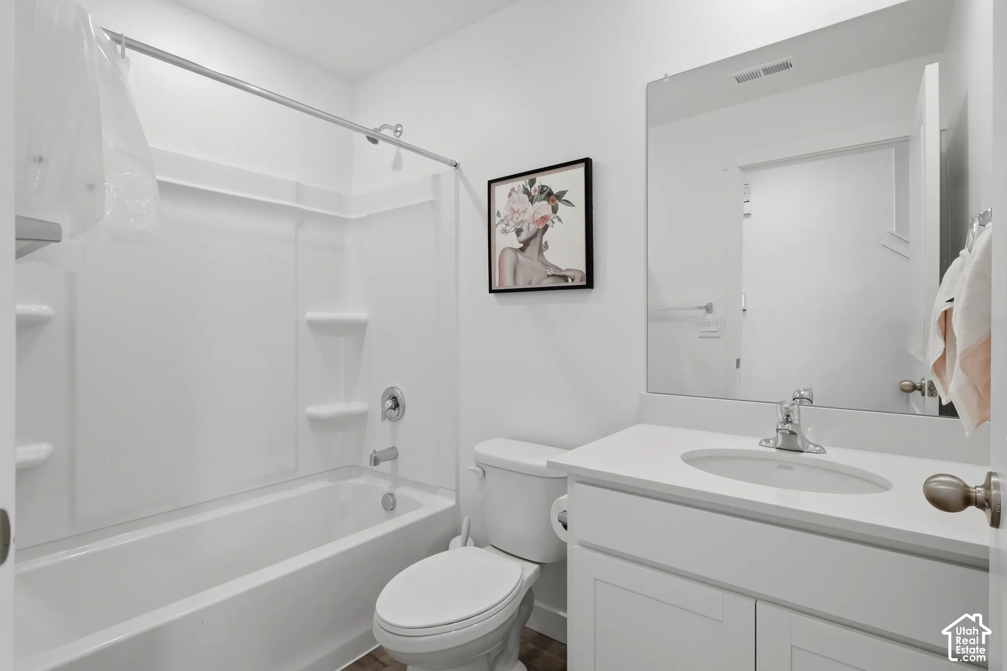 Bathroom featuring a white vanity with an integrated sink, a large wall-mounted mirror, and a tub-shower combination with built-in shelving