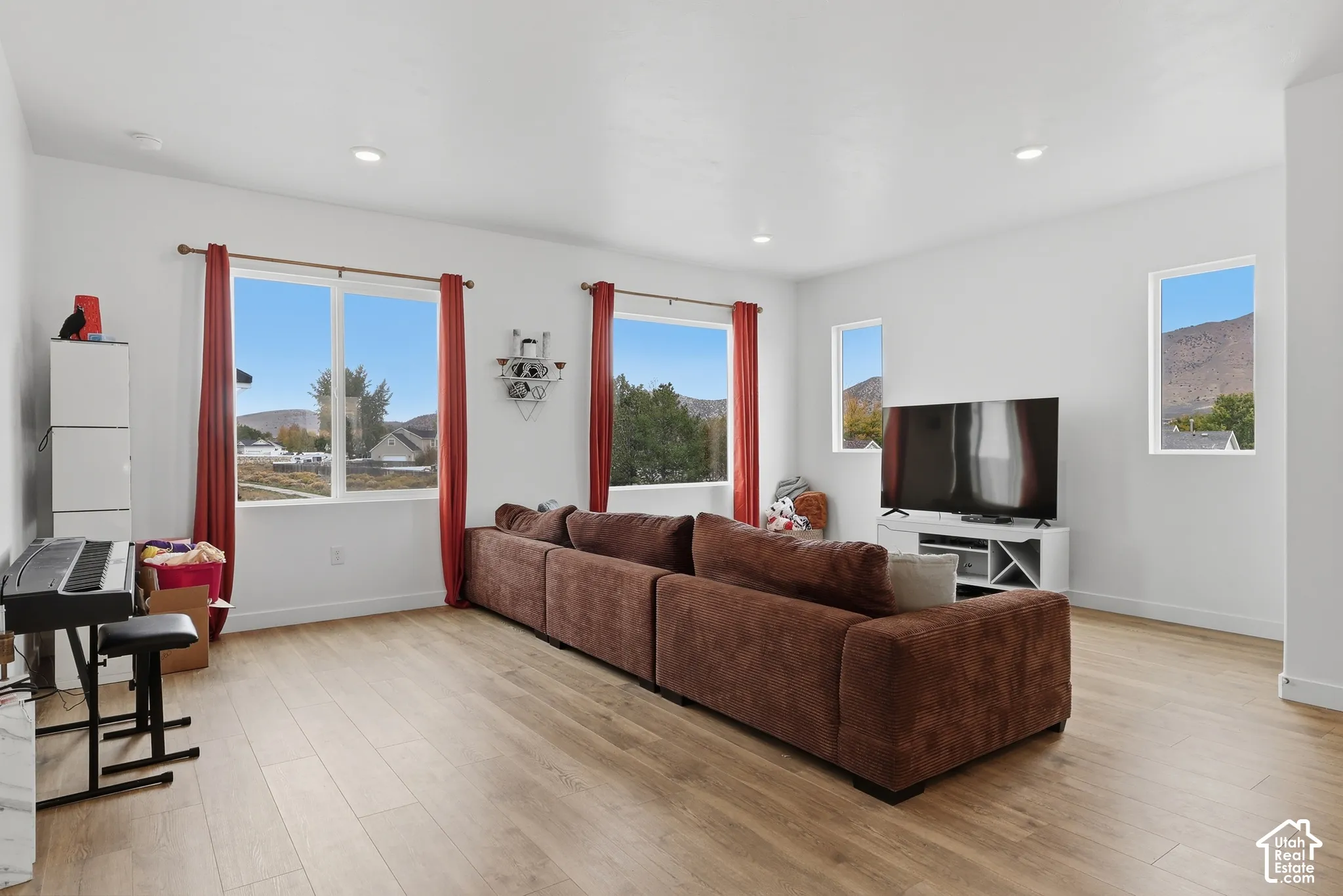 Open-concept interior featuring wood-finish flooring, recessed lighting, and multiple large windows with mountain scenery