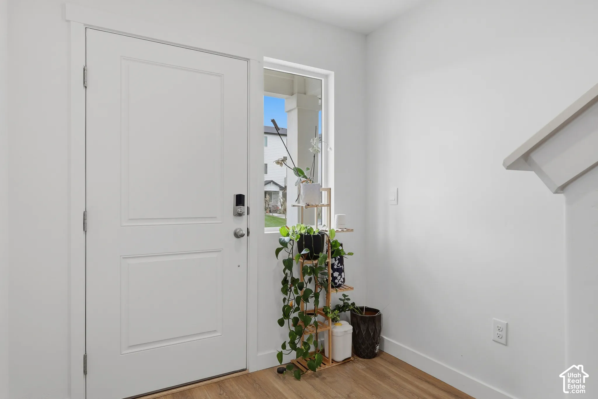 Entryway featuring a white paneled door, vertical side-light window, and wood-finish flooring