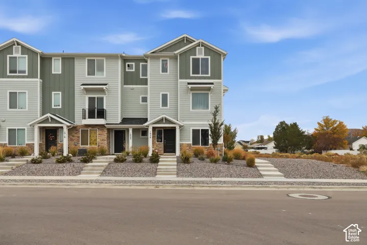 Multi-story exterior featuring horizontal lap siding, vertical board-and-batten accents, stone veneer foundation, covered entryway porches, and second-level balcony