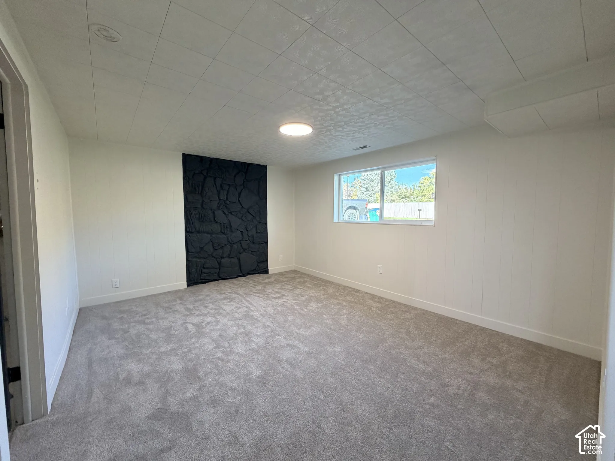 Interior space featuring wall-to-wall carpeting, a dark stone-finish accent wall, and a horizontal window