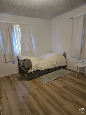 Room featuring wood-finish flooring, textured ceiling, and dual windows