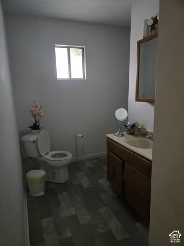 Bathroom featuring wood-finish flooring, a wood vanity cabinet with an integrated sink, a wall-mounted medicine cabinet with a mirror, and a window