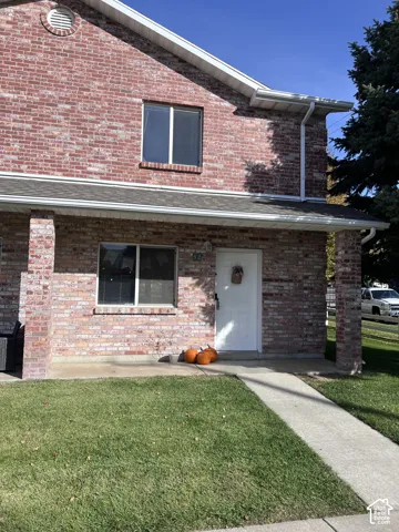 Exterior elevation featuring a full-height red brick facade, covered front porch, concrete walkway, and gable roofline