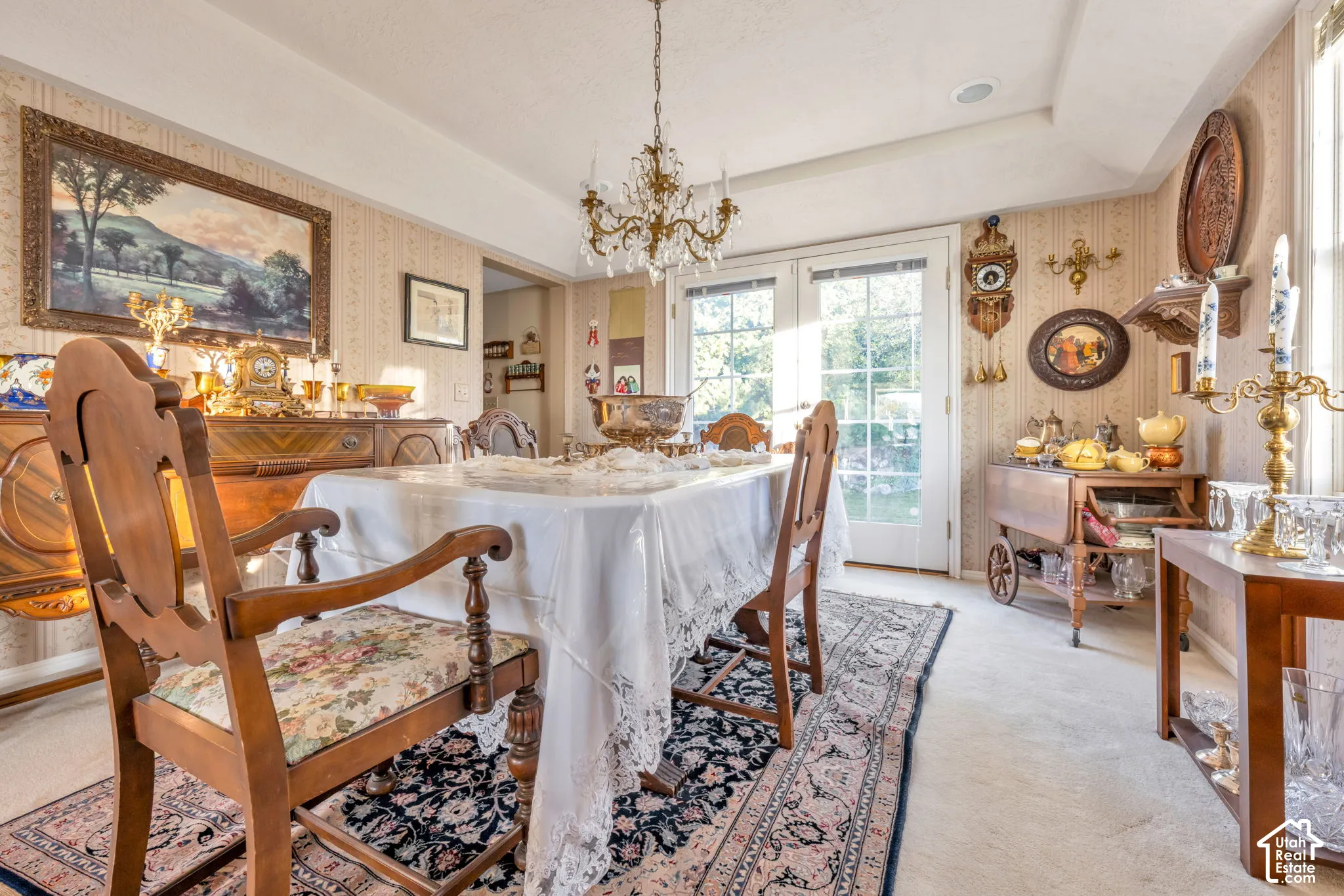 Formal Dining area off the kitchen,  featuring a crystal chandelier, tray ceiling, and double glass-paneled doors that open to the back patio.