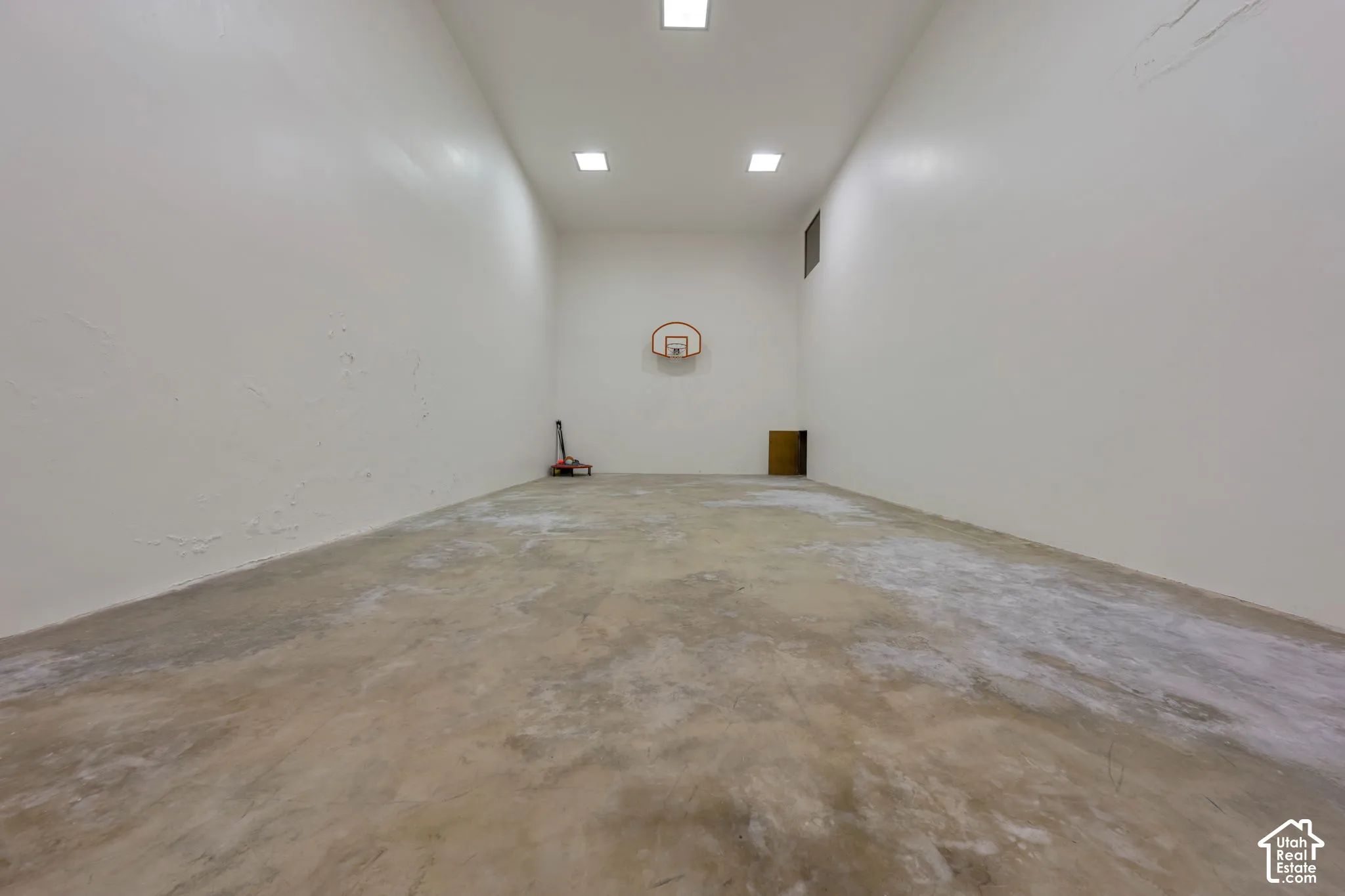 Recreation room featuring high ceilings, concrete flooring, recessed lighting, and a wall-mounted basketball hoop. Accessible from garage entrance stairs and from inside the home.