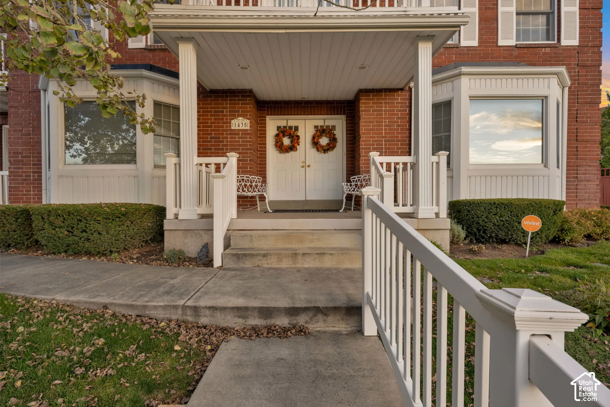 Brick exterior featuring a covered porch with column supports, dual front entry doors, and symmetrical bay windows