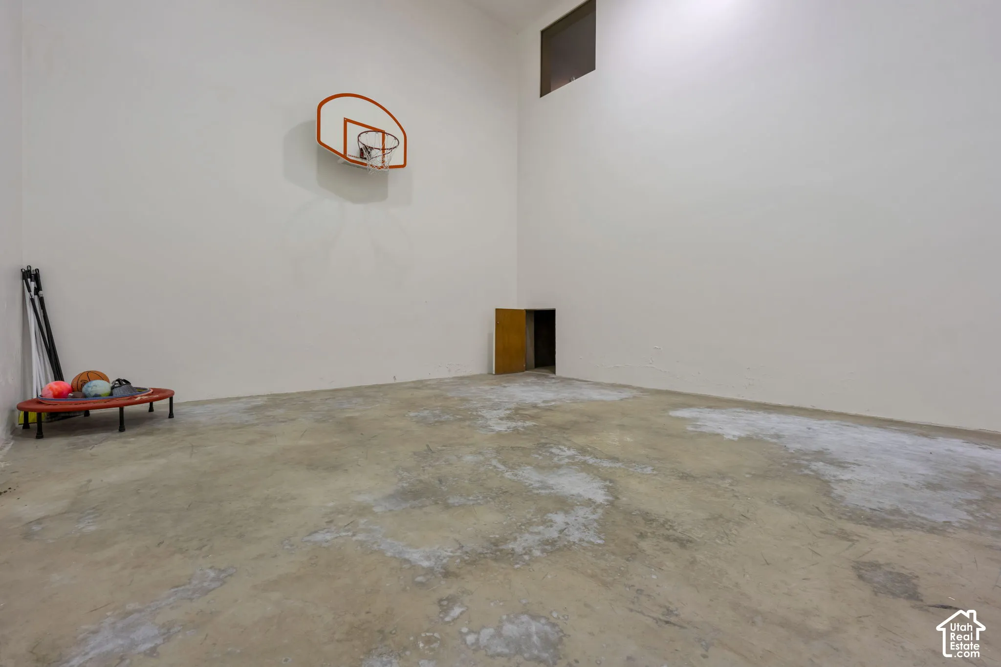 Indoor Huge Recreation/Basketball/Pickleball featuring high ceilings, concrete flooring, and a wall-mounted basketball hoop accessible from garage entry stairwell and inside home.