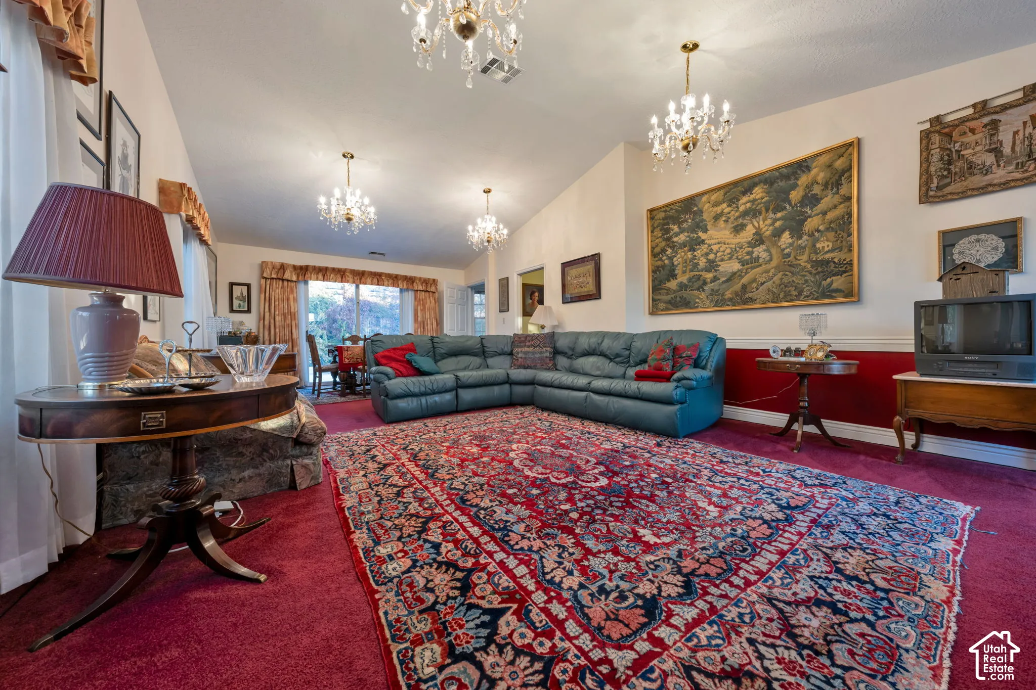 Vaulted ceiling featuring three decorative chandeliers, and sliding glass patio doors