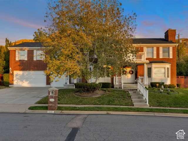 Two-story brick federalist colonial exterior featuring a multi-gabled roofline, a bay window, a heated concrete driveway, and two second-story balconies
