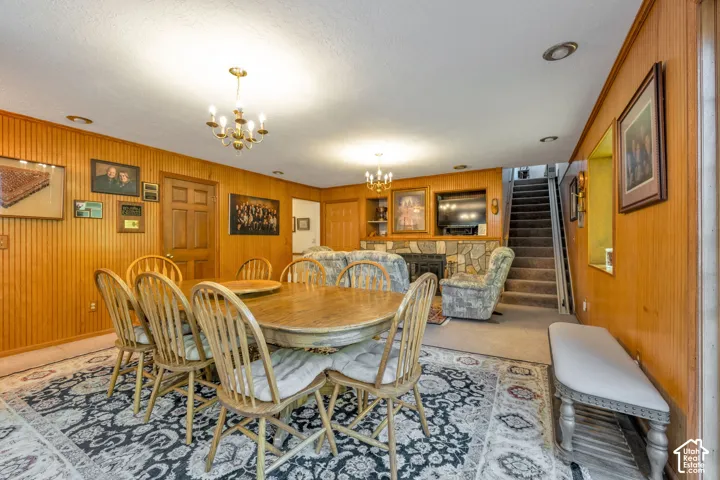 Wood-paneled walls, stone-surround fireplace, two multi-arm chandeliers