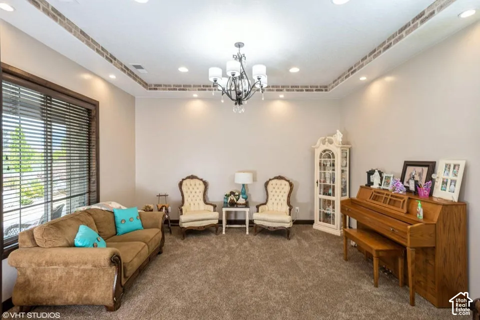 Tray ceiling featuring brick-accented border, recessed lighting, and a multi-arm chandelier