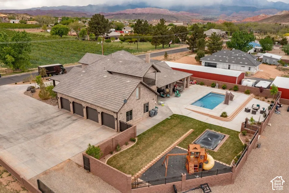 Exterior features include a multi-car garage, concrete patio, swimming pool, fenced yard with manicured lawn, and mountain scenery