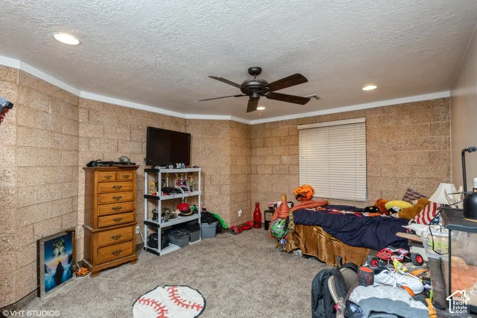 Exposed masonry block walls, carpeted flooring, recessed lighting, and a ceiling fan