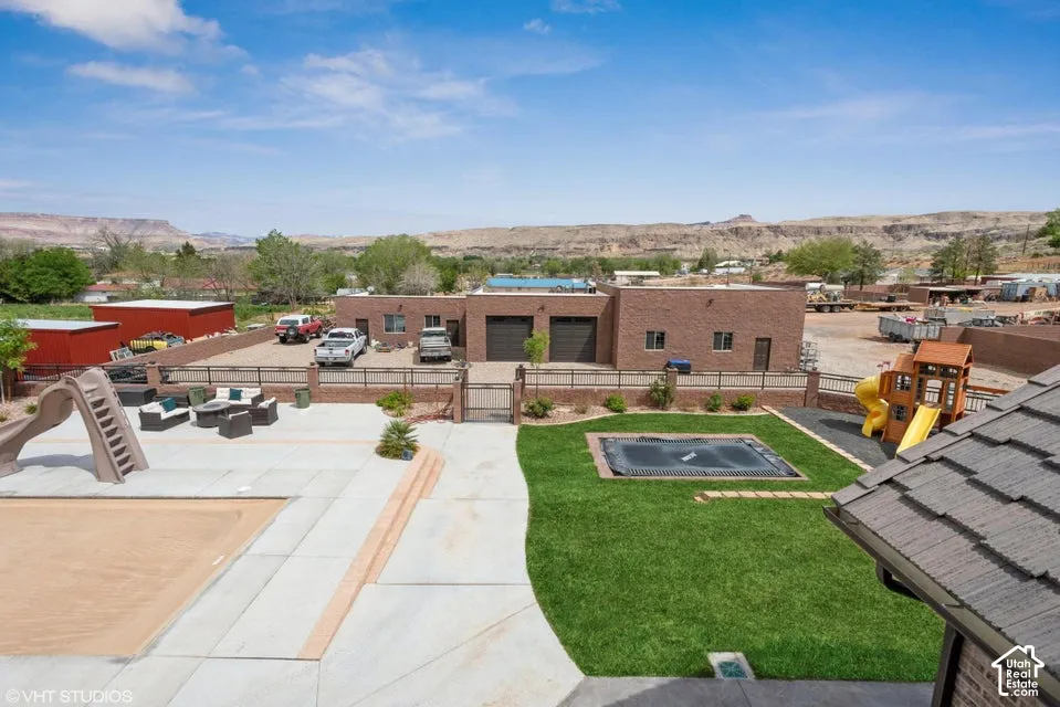 Expansive backyard featuring a concrete patio, an in-ground pool, a level lawn with a built-in trampoline, and mountain scenery
