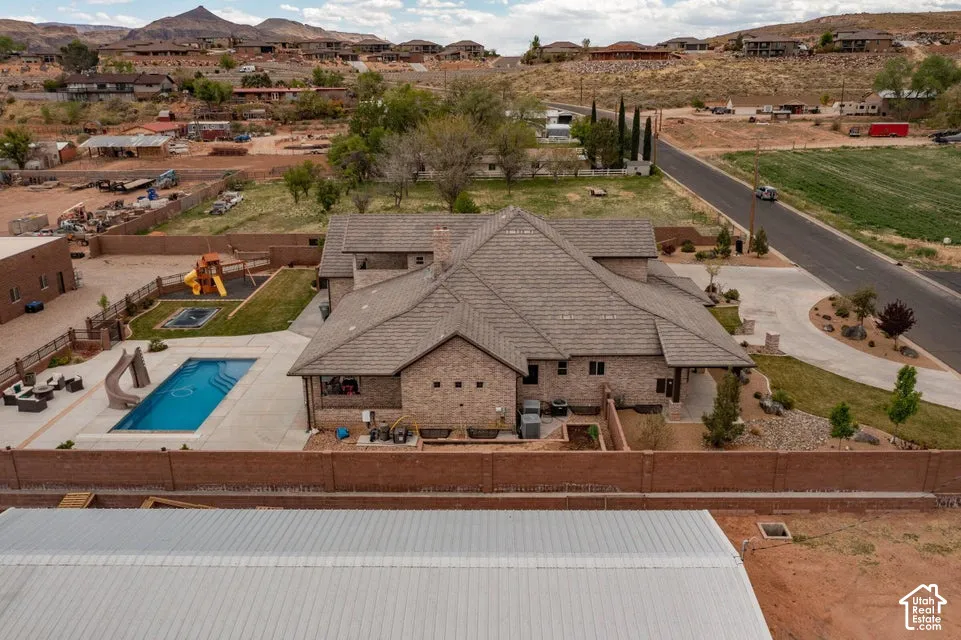 Brick exterior residence featuring a concrete tile roof, in-ground swimming pool with an integrated slide, sprawling manicured lawn, and perimeter masonry walls