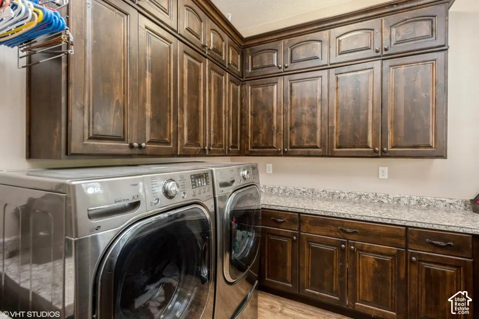 Laundry space featuring custom wood cabinetry, stone-patterned countertops, and upper and lower storage configuration