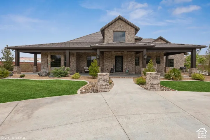 Stone veneer exterior featuring an expansive covered porch, metal roofing, concrete driveway, and custom decorative front door