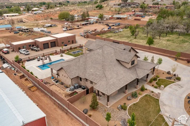 Multi-structure property featuring a main residence with a hipped tile roof, an in-ground swimming pool, a detached garage, and masonry perimeter wall fencing