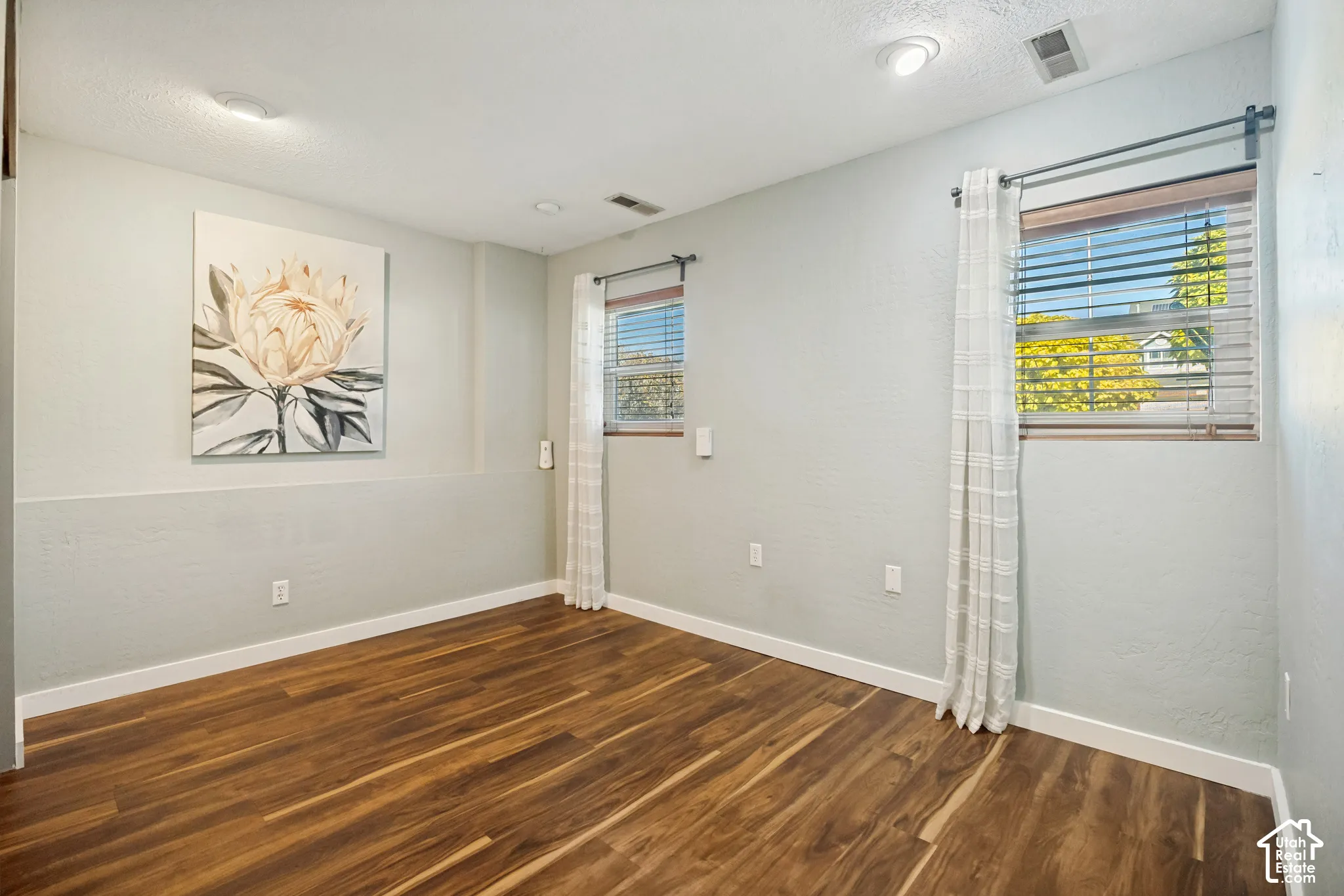 Room featuring wood-finish flooring, recessed lighting, and two windows with horizontal blinds