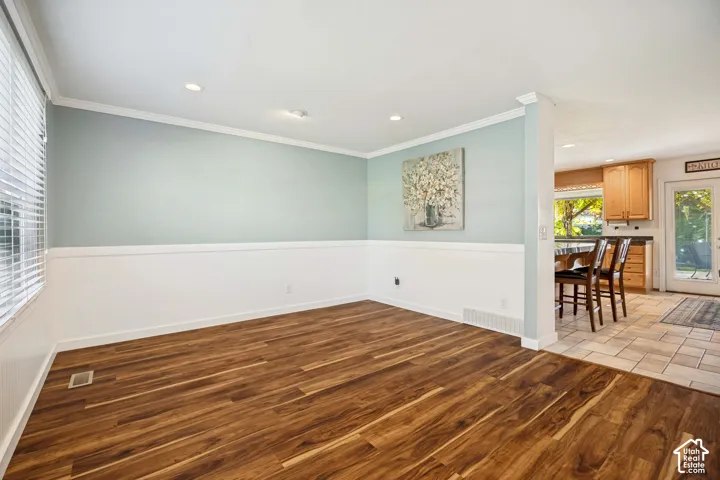 Wood-finish flooring, wainscoting, recessed lighting, and crown molding