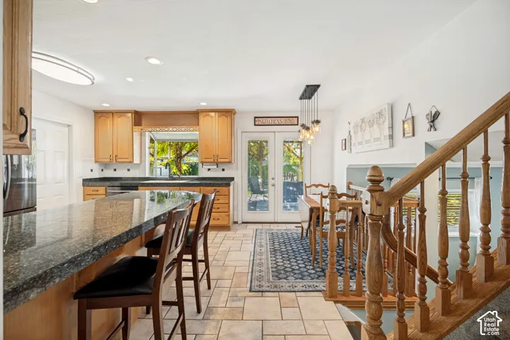 Kitchen featuring wooden cabinetry, dark stone-finish countertops, tile flooring, and double glass-pane doors