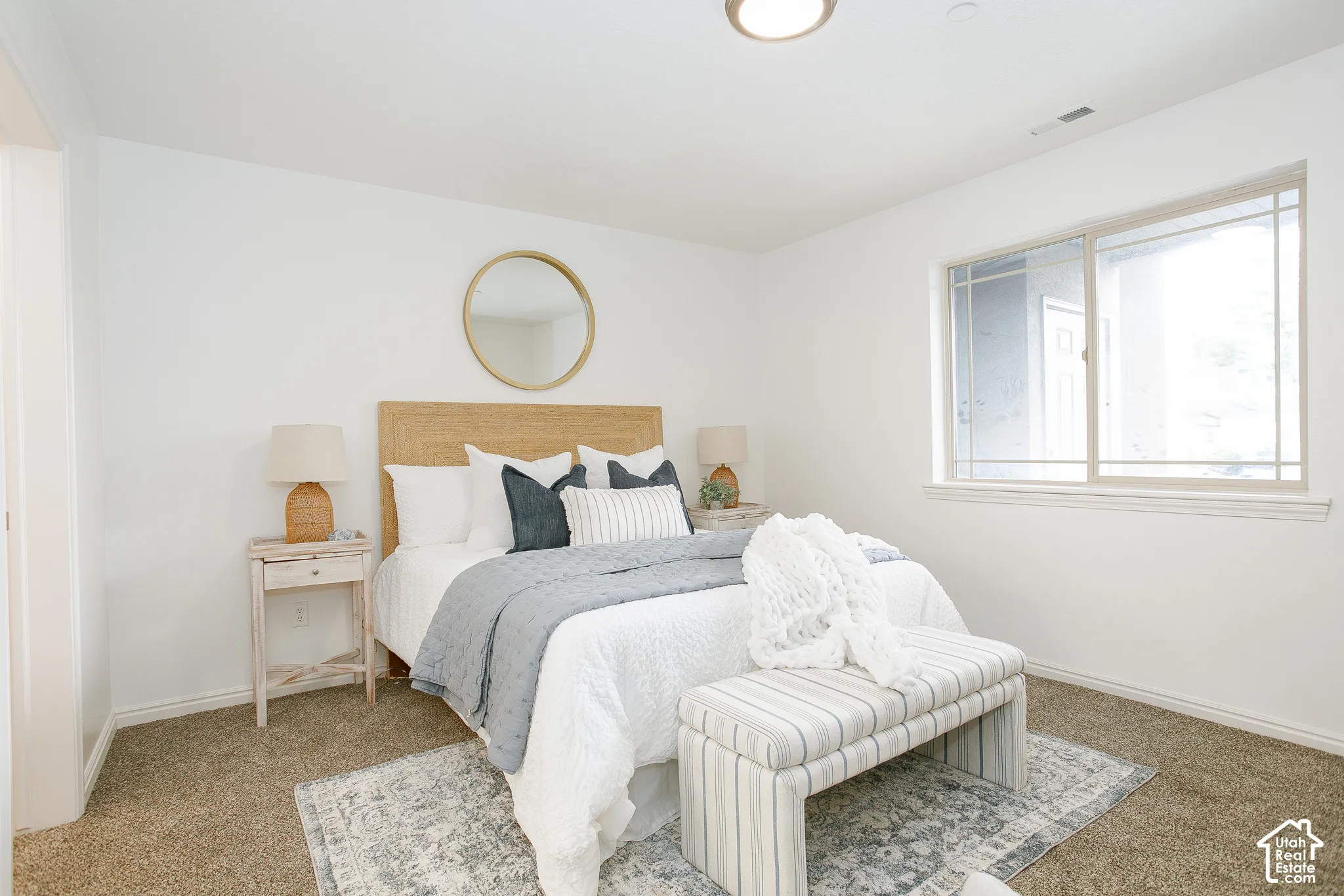 Neutral-toned carpeted flooring, large window with natural lighting, and ceiling-mounted lighting fixture
