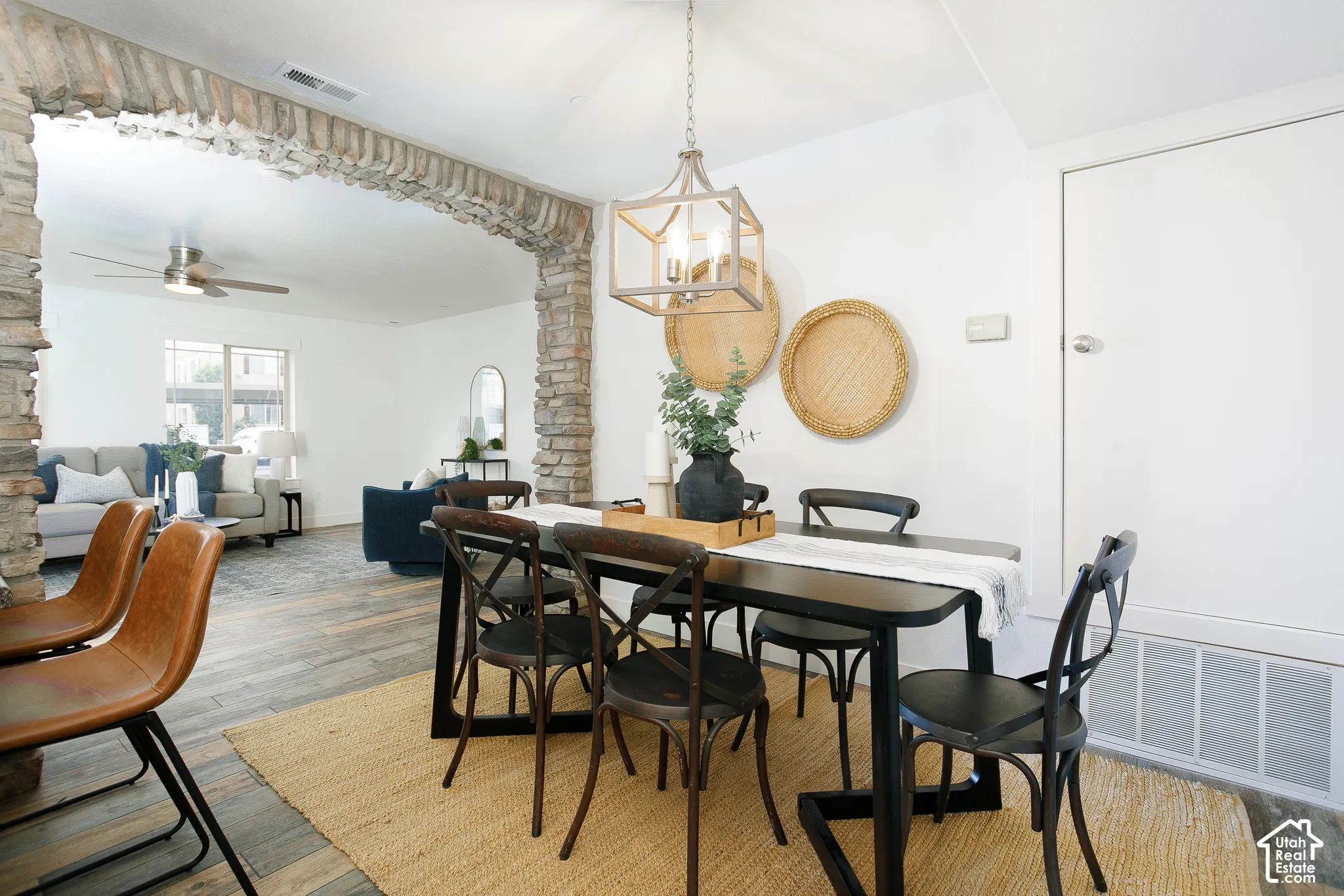 Interior space featuring a rustic stone archway, wood-finish flooring, and a geometric metal-frame pendant light fixture