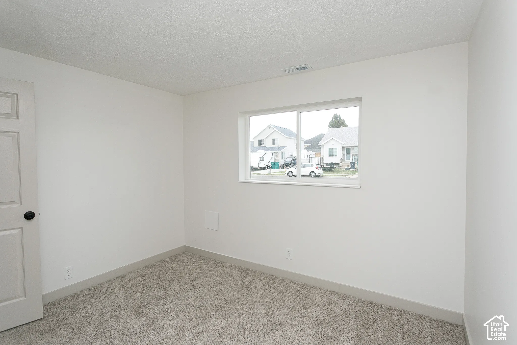 Neutral interior room featuring neutral-toned carpeting, white walls, and a sliding glass window