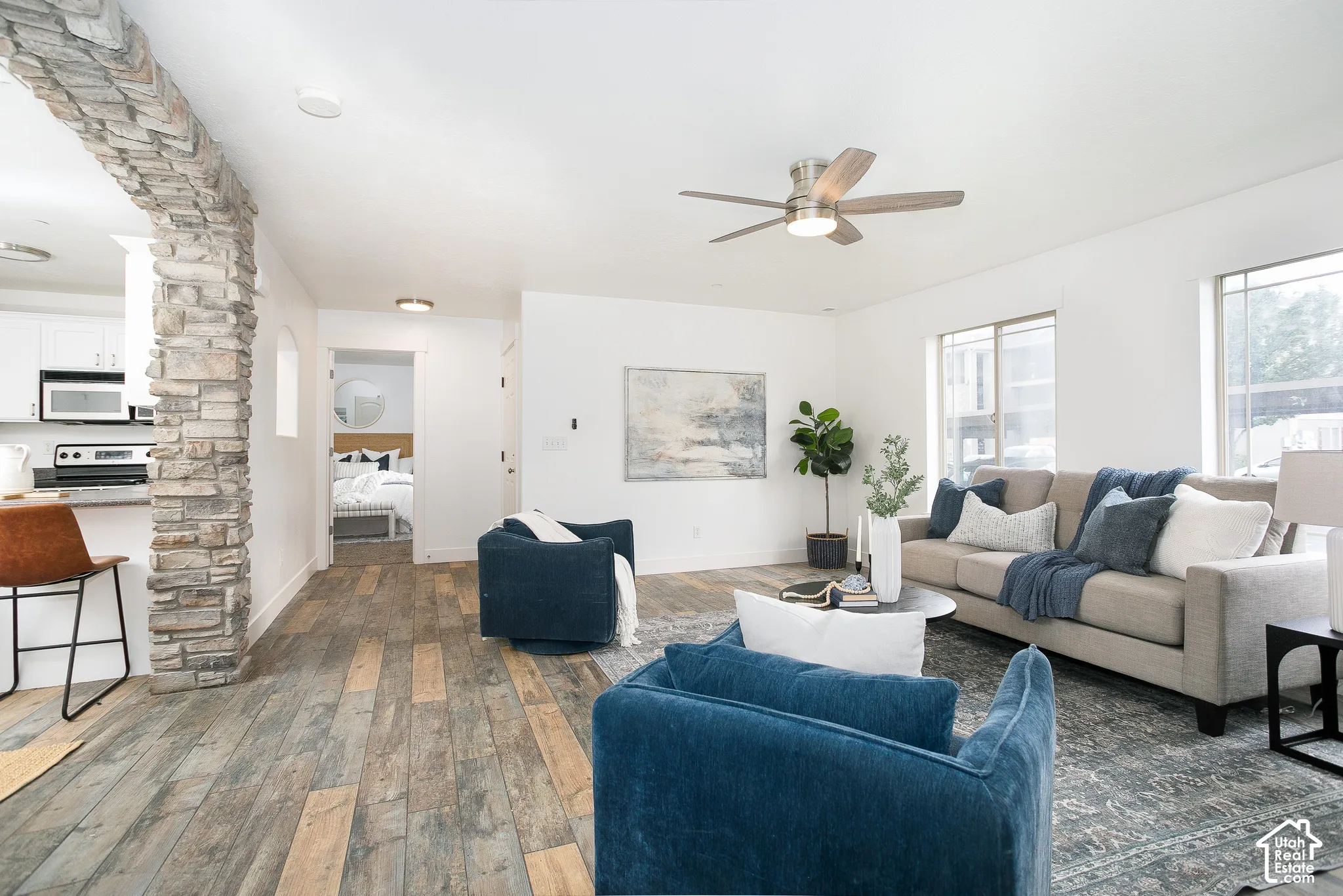 Living area featuring a floor-to-ceiling stone archway, wood-finish flooring, and a ceiling fan with integrated lighting