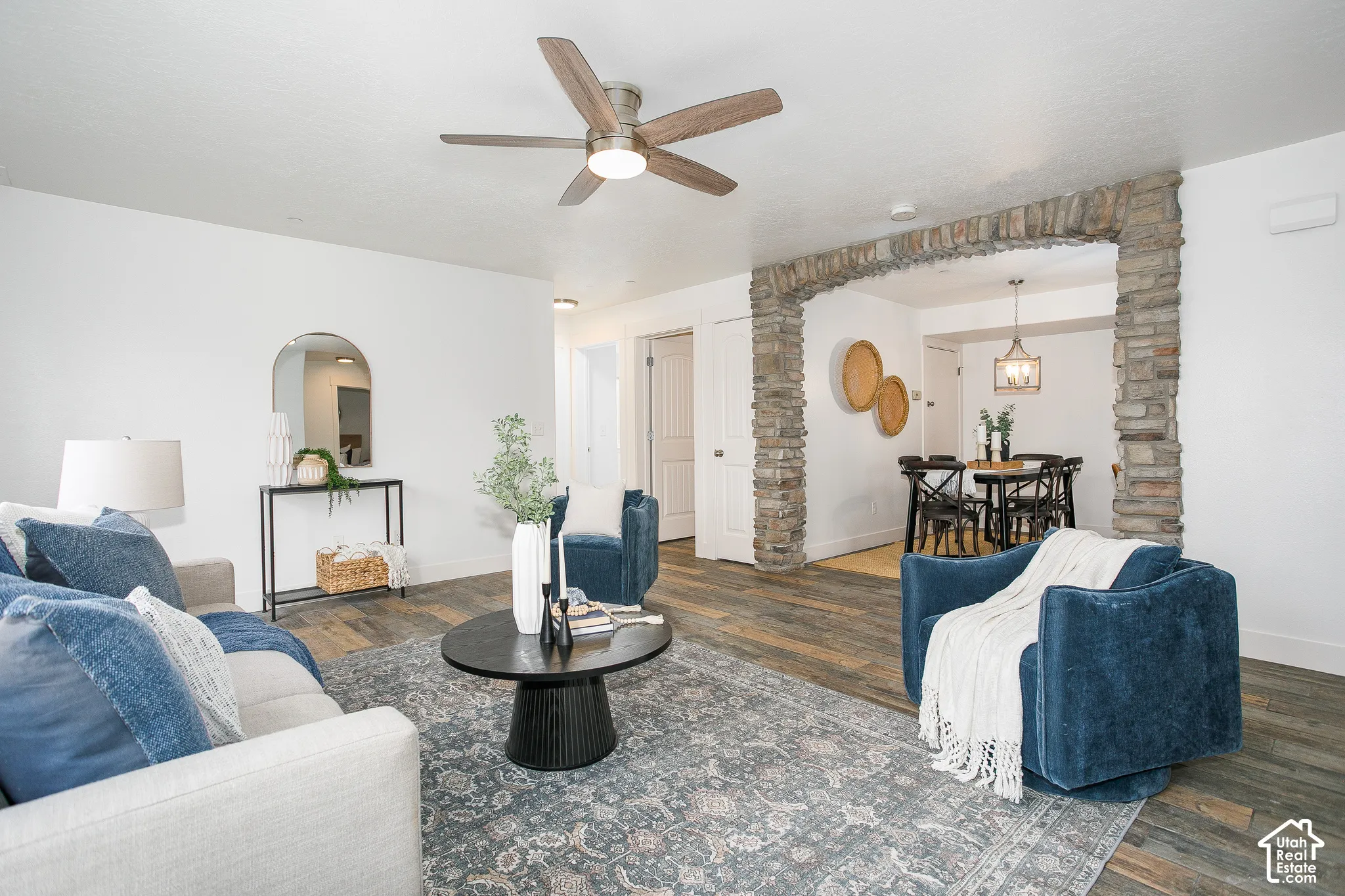 Interior space featuring wood-finish flooring, stone masonry archway, and ceiling fan with integrated lighting