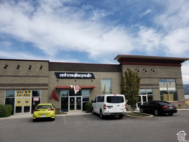 Commercial exterior featuring a split-faced concrete masonry facade, large storefront glass windows, multi-level flat roofline, and integrated gooseneck exterior lighting