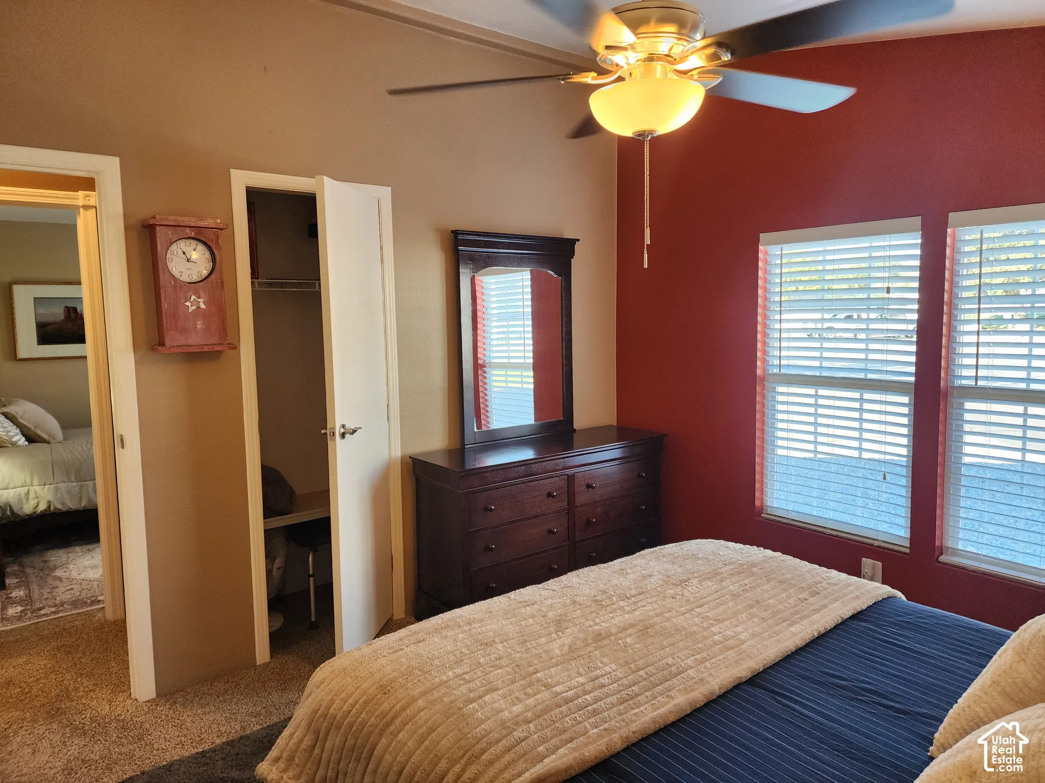 Room featuring carpeted flooring, two windows with horizontal blinds, and a ceiling fan with integrated lighting