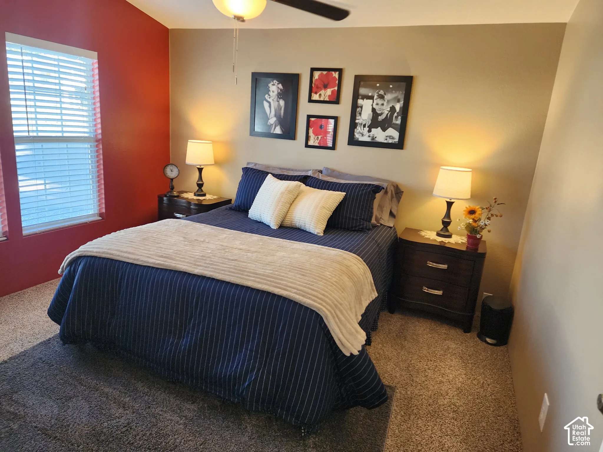 Bedroom featuring neutral wall paint with a vibrant accent wall, carpeting, and an attached ceiling fan with lighting
