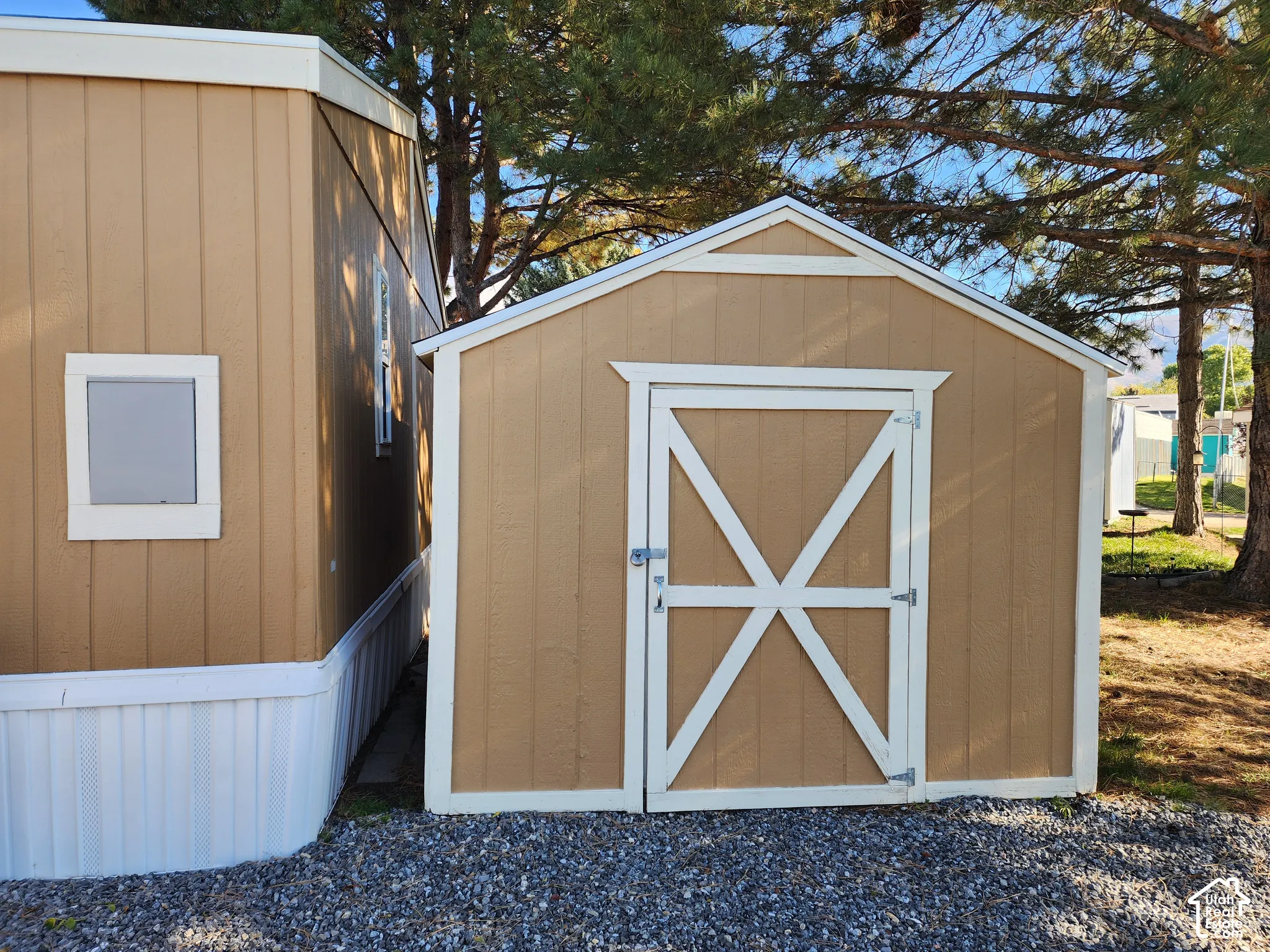 Exterior storage shed featuring paneled wood-composite siding, a gabled roofline, and contrasting trim