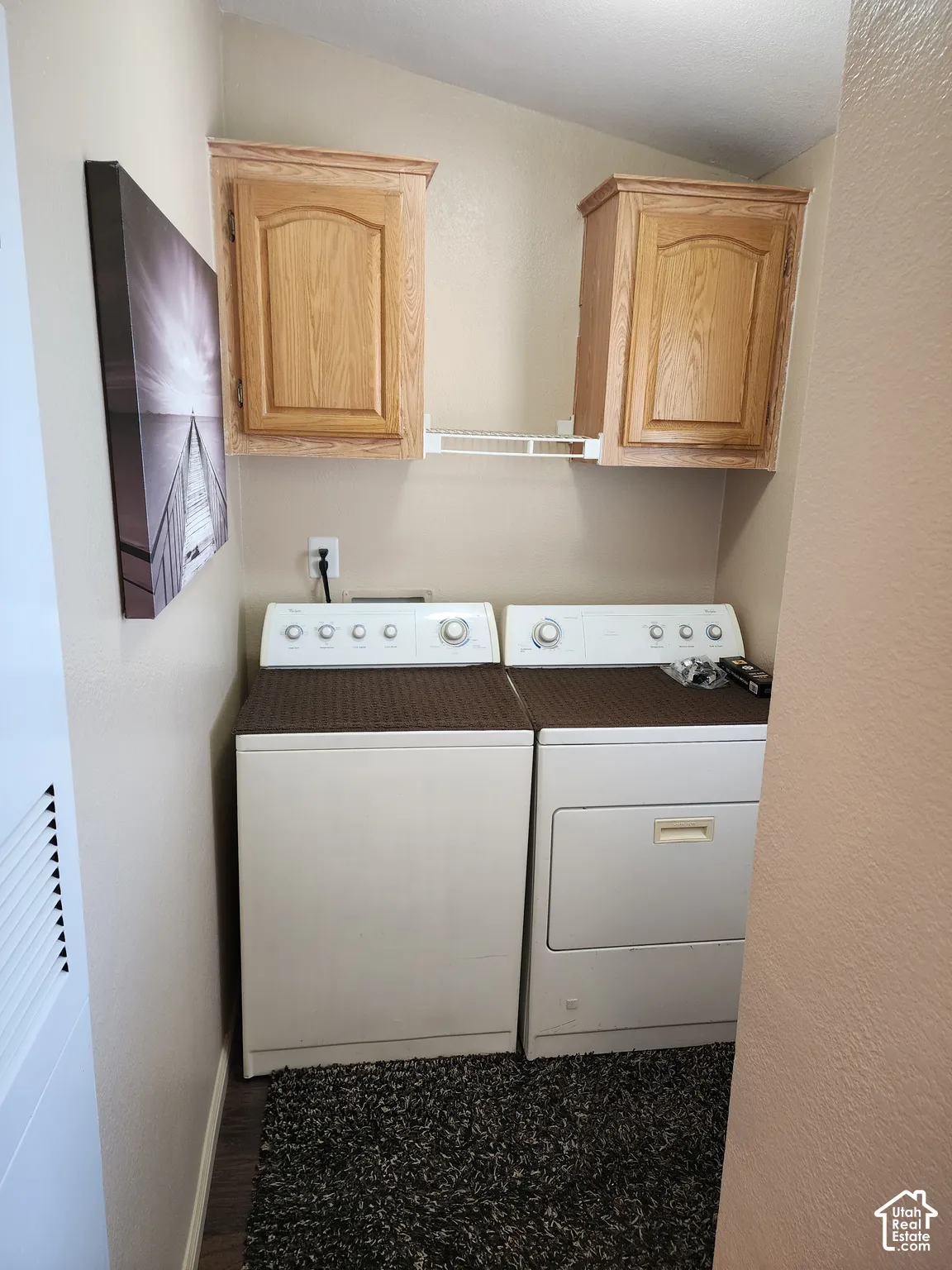 Laundry area featuring dual wall-mounted wood-finish cabinets and a fixed wire shelving unit