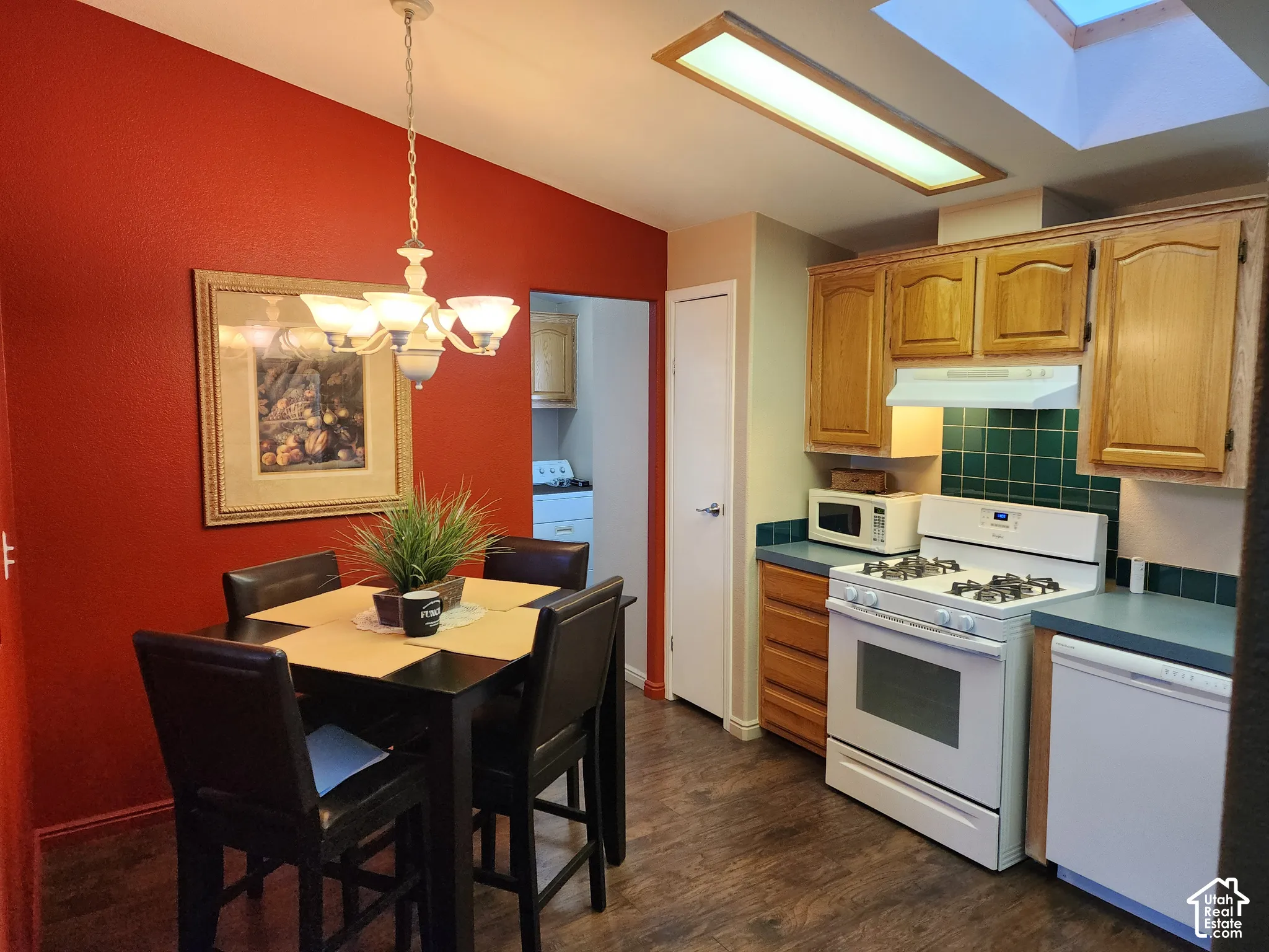 Kitchen featuring wood-finish flooring, a skylight, raised-panel wood cabinetry, a tiled backsplash, and built-in appliances