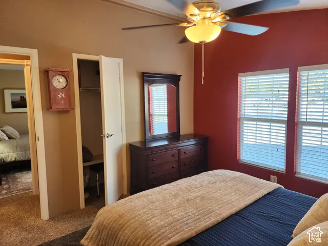 Room featuring carpeted flooring, two windows with horizontal blinds, and a ceiling fan with integrated lighting