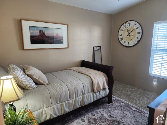 Neutral-toned interior walls, window with adjustable blinds, and textured wall-to-wall carpeting