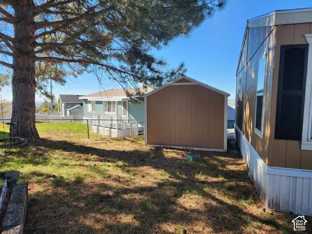 Exterior lot space featuring a detached storage shed, mature coniferous tree, and metal chain-link fencing