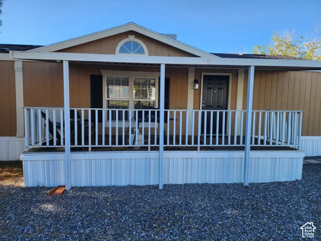 Covered front porch featuring white railing and support posts, gable roofline with decorative arched transom window, and vertical siding exterior