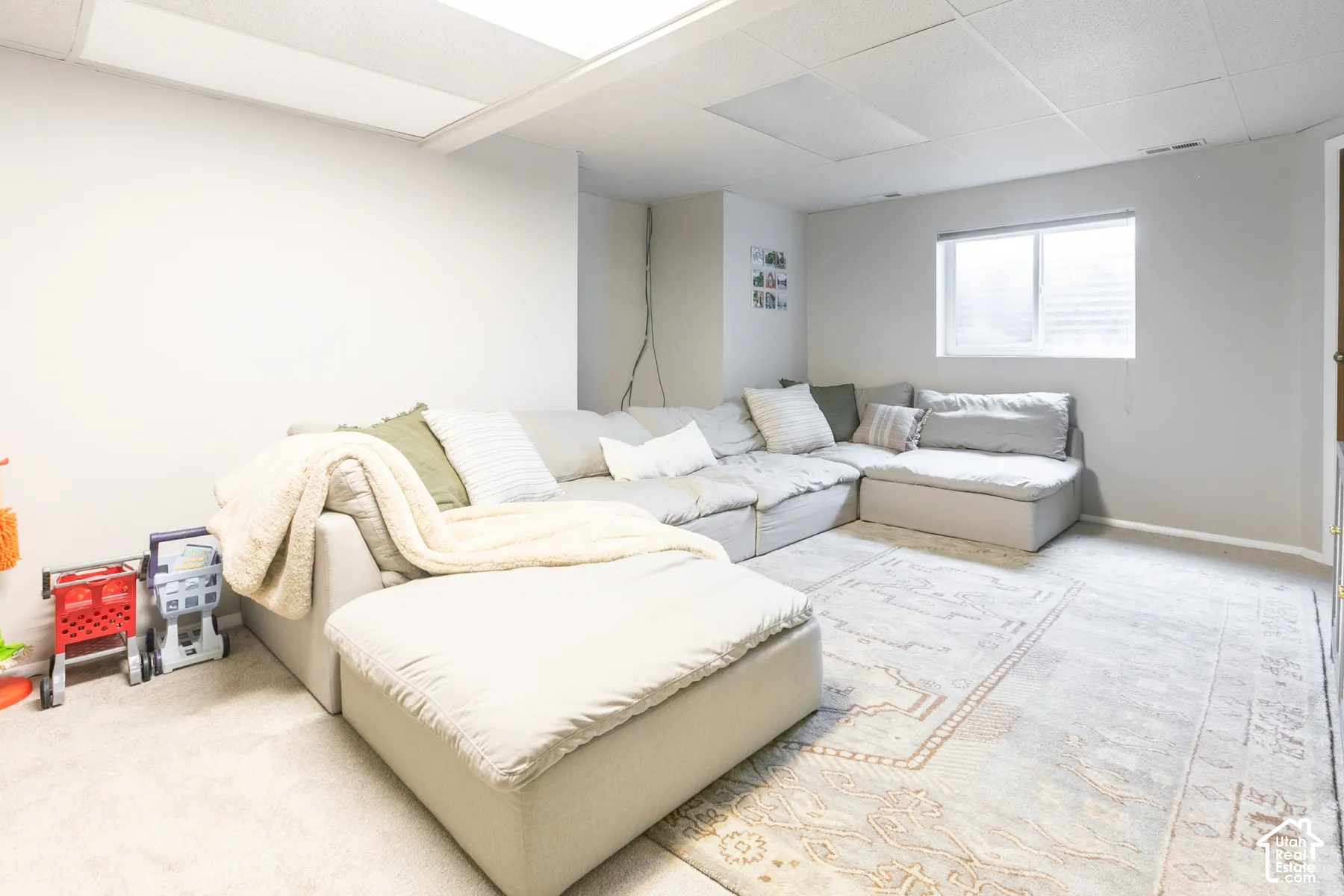 Finished space featuring a drop ceiling with recessed lighting, carpeted flooring, and a single window with natural light