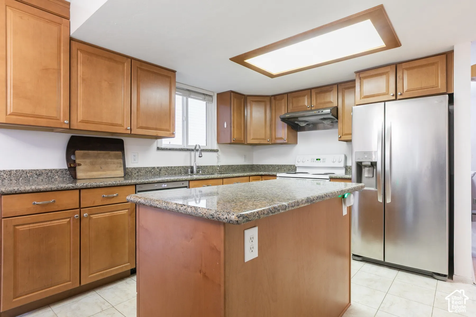Kitchen featuring natural wood cabinetry, stone-finish countertops, stainless steel side-by-side refrigerator, recessed lighting, and a center island
