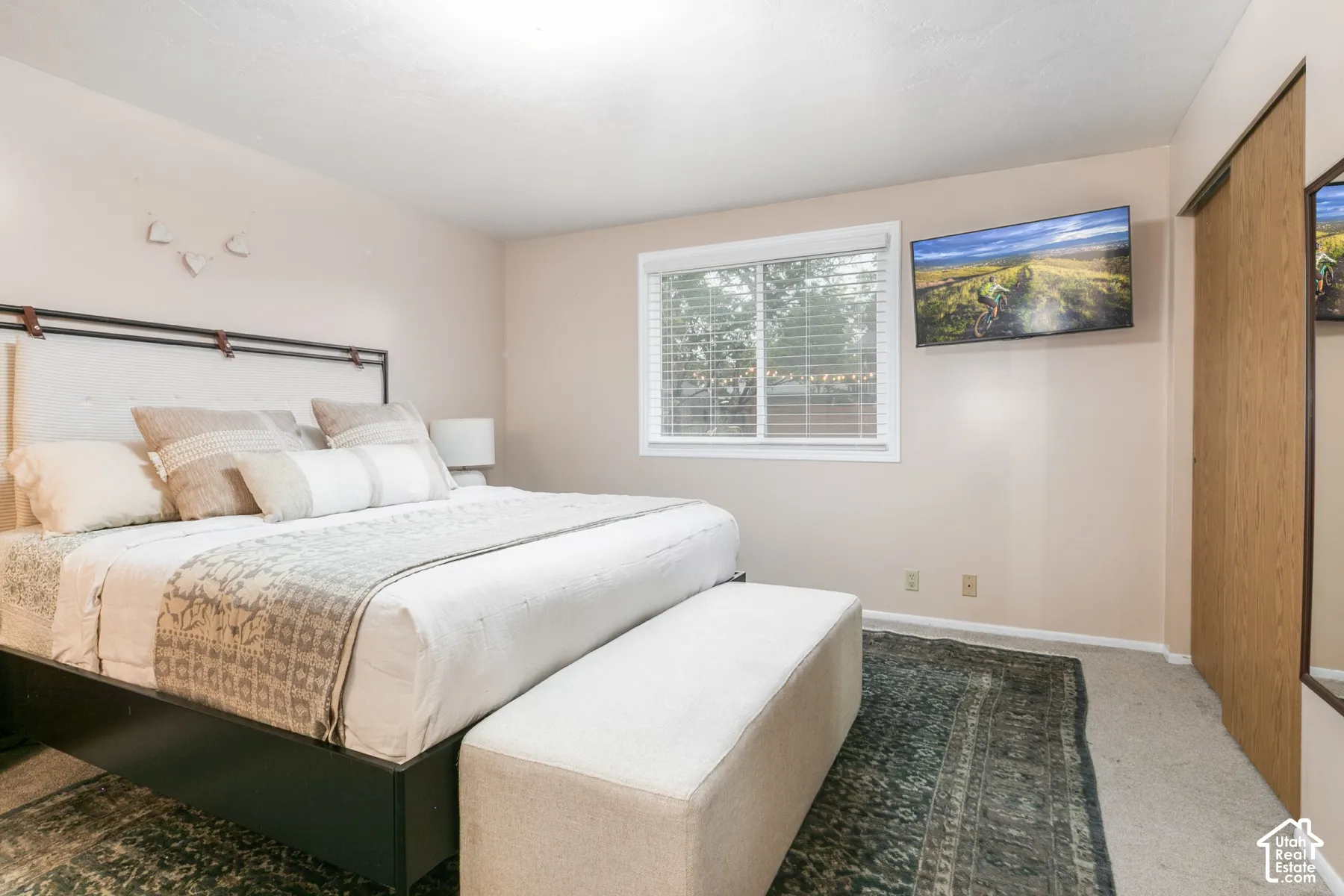 Bedroom featuring carpeting, a multi-pane window with white frame, and a sliding closet door with a wood finish