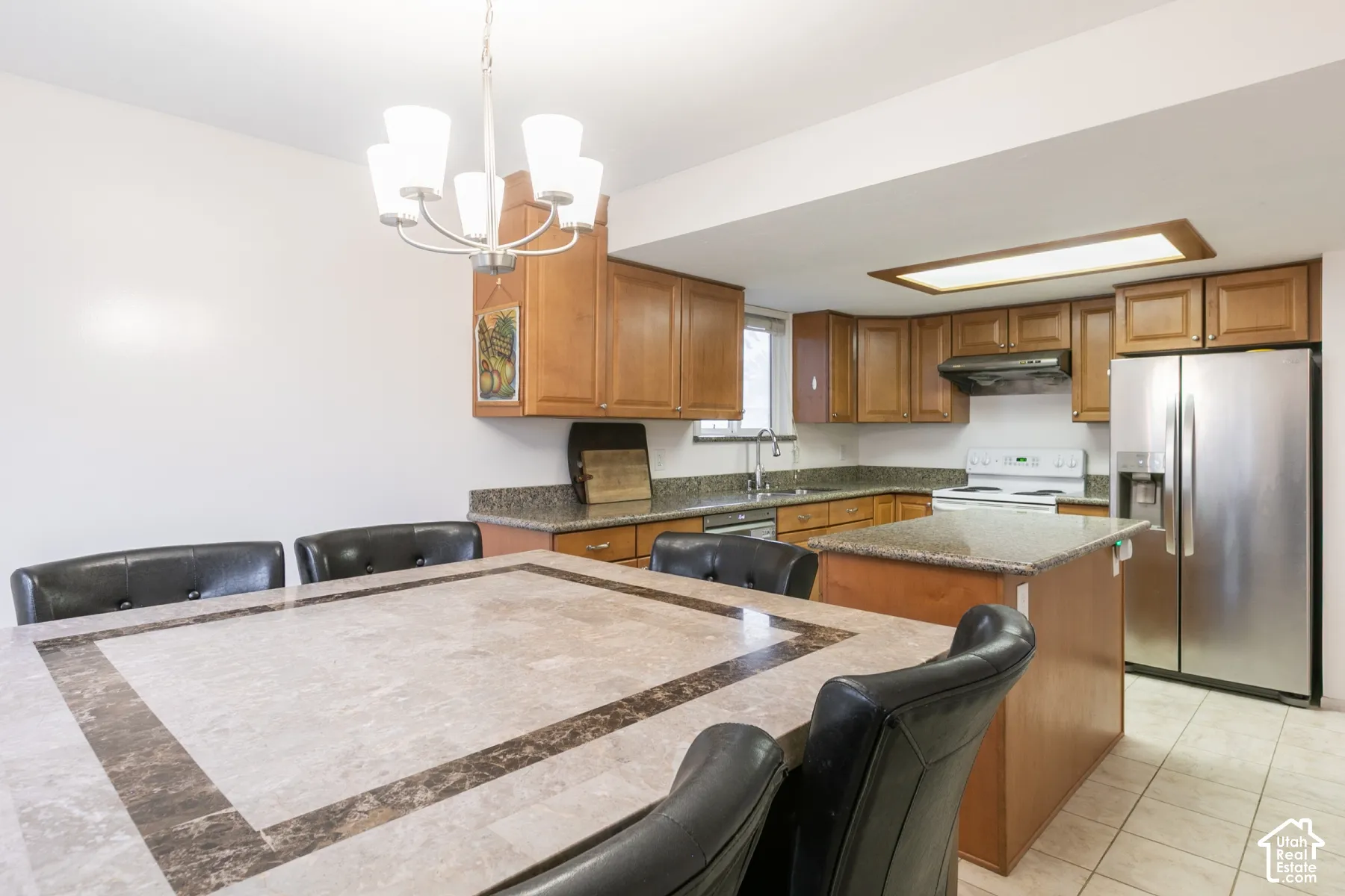 Kitchen featuring wood cabinetry, stone-surface countertops, center island, stainless steel refrigerator, and integrated lighting
